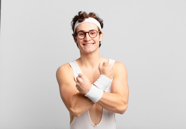 Homem do esporte bem humorado, sorrindo alegremente e comemorando, com os punhos cerrados e os braços cruzados, sentindo-se feliz e positivo