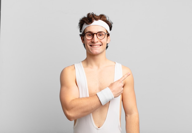 homem do esporte bem-humorado sorrindo alegremente, sentindo-se feliz e apontando para o lado e para cima, mostrando o objeto no espaço da cópia