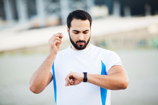 Homem do esporte usando fones de ouvido para ouvir música na corrida matinal no parque.