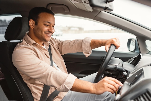 Homem do motorista do Oriente Médio apertando botões no painel dirigindo auto