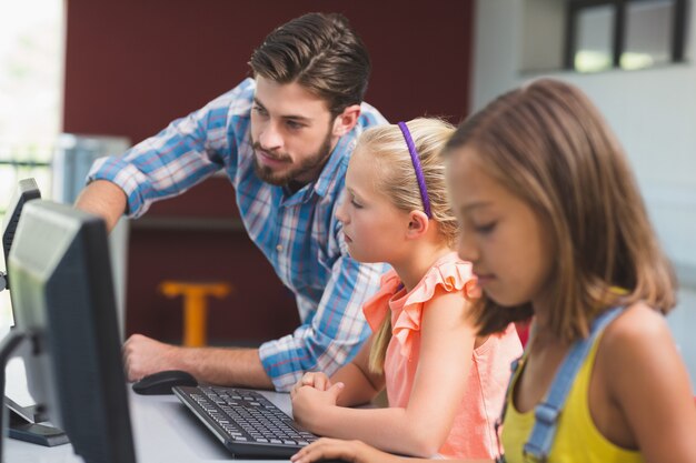 Homem do professor que ajuda estudantes em aprender o computador