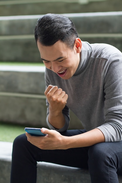 Homem do sudeste asiático animado usando smartphone