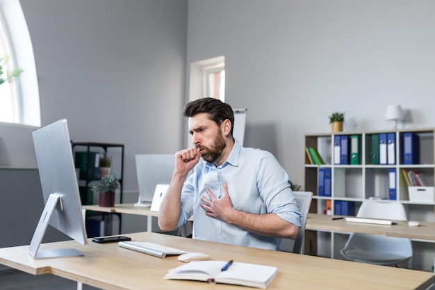 Homem doente que trabalha no escritório tem um empresário tossindo tosse ruim no computador