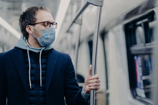 Homem doente respira através de máscaras médicas viaja por transporte público protege contra coronavírus ou gripe trabalha no subsolo usa óculos e capuz Conceito de doença pandêmica