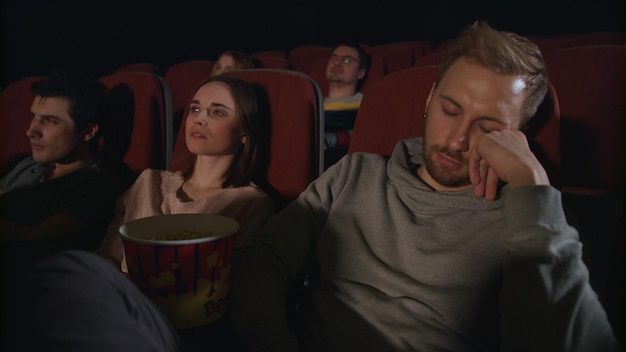 Foto homem dorme no cinema cara dormindo no cinema as pessoas assistem a um filme chato