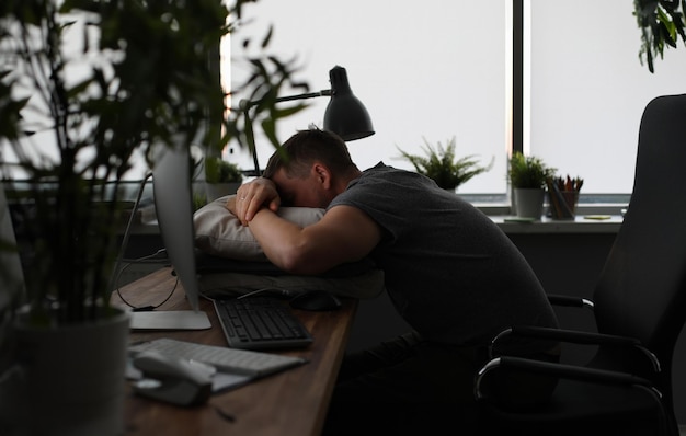 Homem dormindo na mesa do escritório fundo noturno Homem quer ir para casa e vive no trabalho Conceito de trabalho noturno de horas extras