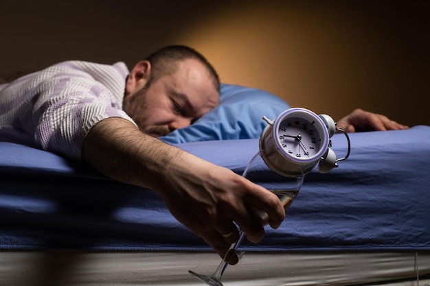 Homem e alcoolismo Ficar bêbado com álcool e dormir demais o conceito de despertador Agonia de ressaca pela manhã Beber álcool para dormir