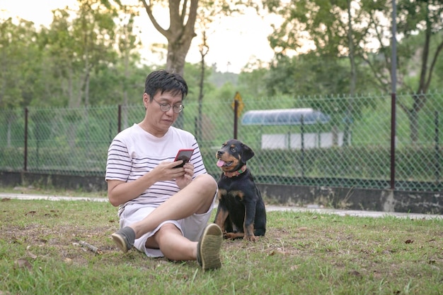 Homem e cão de estimação sentam-se juntos na grama do parque