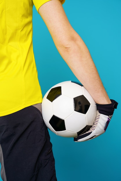 Homem é fã de futebol com camiseta amarela e bola de futebol no azul