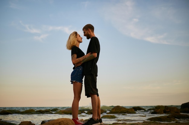 homem e menina caucasianos se abraçando à beira-mar na praia ao pôr do sol