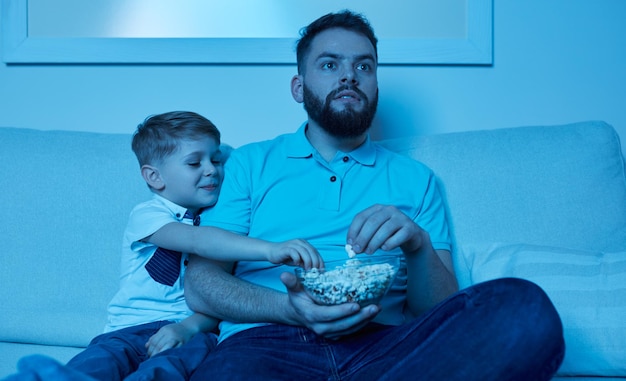 Homem e menino assistindo filme à noite