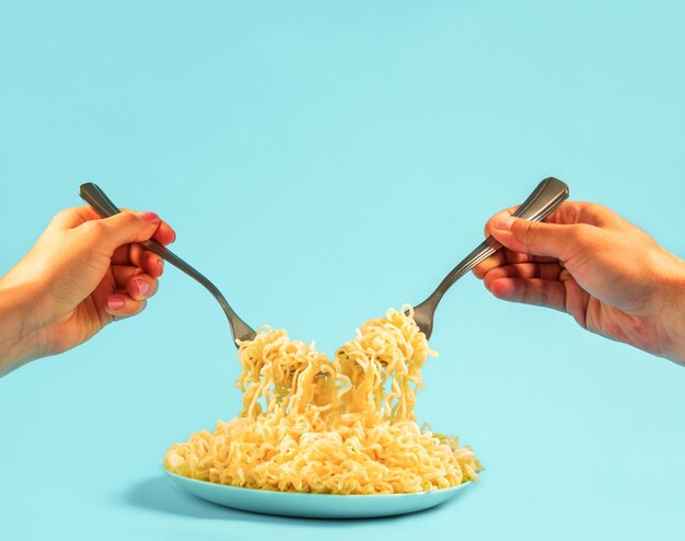 Homem e mulher a comer espaguete juntos, mãos femininas e masculinas com garfos e pasta.