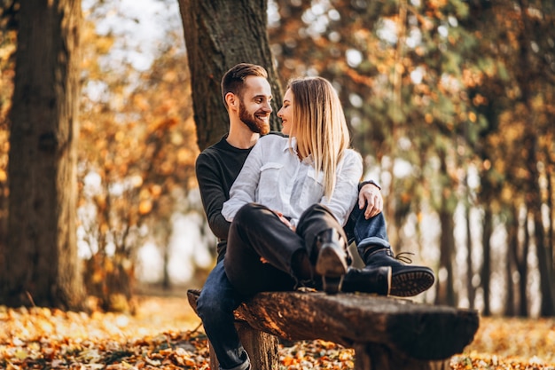 Homem e mulher, abraçando e sorrindo no fundo das árvores de outono.