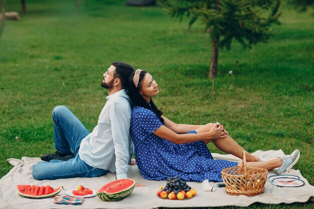 Homem e mulher adulta jovem casal piquenique no prado de grama verde no parque.
