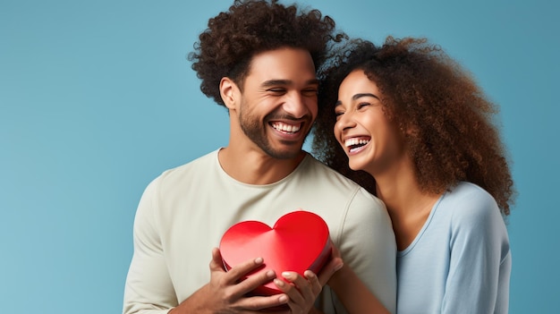 Homem e mulher alegres de frente um para o outro sorrindo alegremente enquanto seguram um presente vermelho em forma de coração entre eles