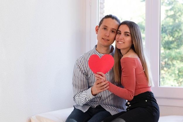 Homem e mulher apaixonados jusetando um coração vermelho e com espaço de cópia