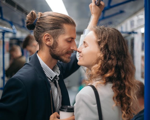 Homem e mulher apaixonados olhando um para o outro em um trem do metrô