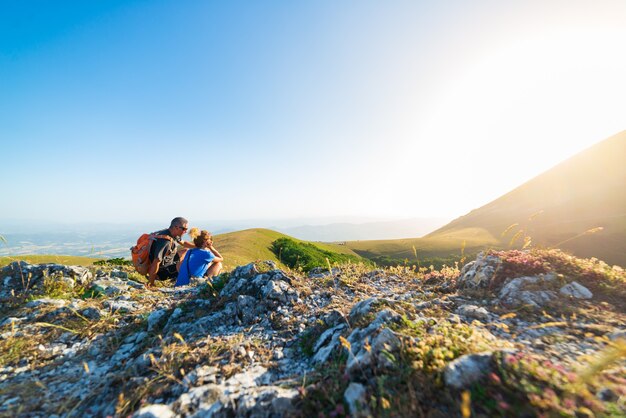 Homem e mulher, caminhadas nas montanhas da região de umbria, monte cucco, appennino, itália. casal assistindo pôr do sol juntos no topo da montanha. atividade ao ar livre de verão.