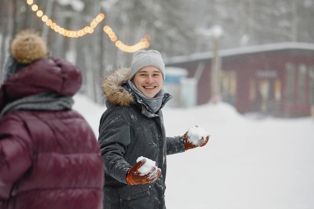 Homem e mulher com roupas de inverno brincando na neve do parque