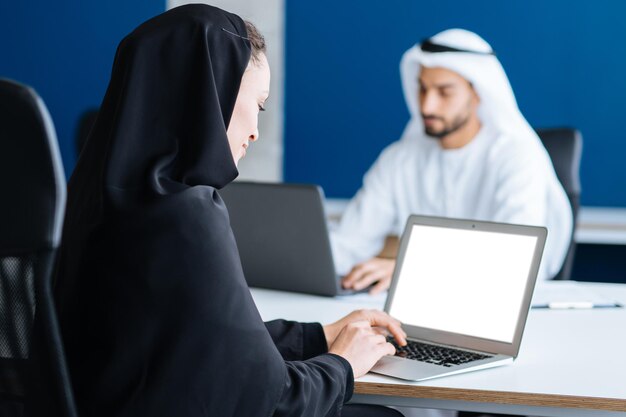 Homem e mulher com roupas tradicionais trabalhando em um escritório de negócios de Dubai