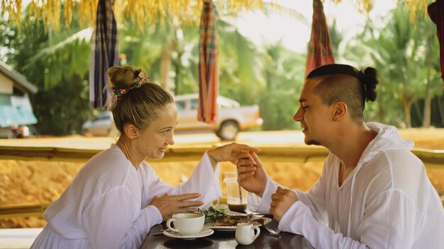 Homem e mulher comem e bebem bebidas saborosas passando tempo no tradicional café flutuante local