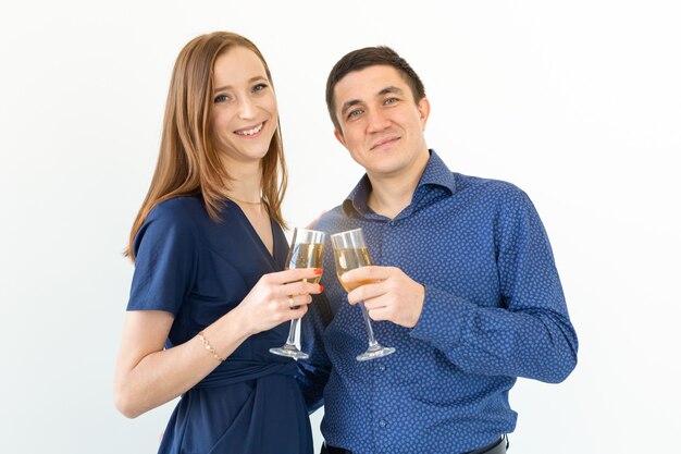 Homem e mulher comemorando o natal ou a festa de véspera de ano novo com taças de champanhe no fundo branco.
