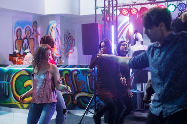 Homem e mulher dançando e festejando na discoteca reunida em boate. Jovem casal caucasiano improvisando e fazendo movimentos na pista de dança enquanto batia e frequentava a discoteca