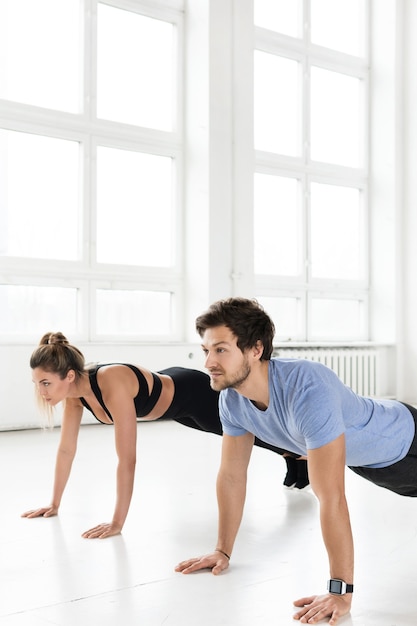 Homem e mulher de aptidão durante o treino com no ginásio. exercícios de flexões para os músculos do peito e tríceps.