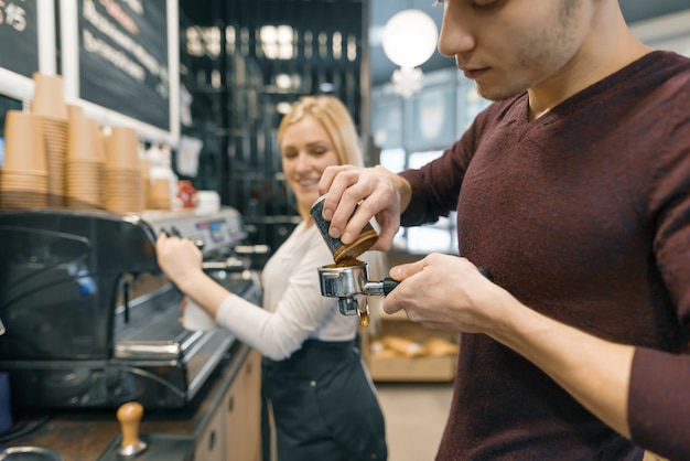 Homem e mulher de Barista que fazem o café, pares de jovens que trabalham na cafetaria.