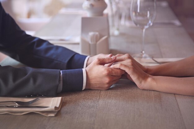 Homem e mulher de mãos dadas juntos no restaurante closeup