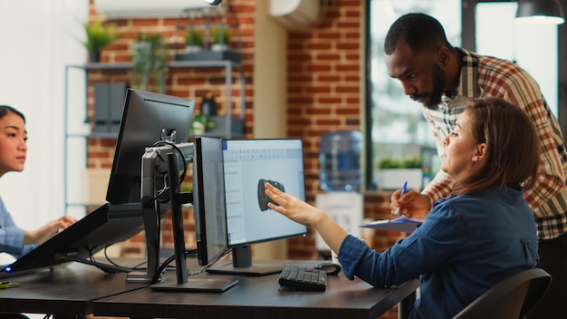 Homem e mulher discutindo ideias para criar um novo software industrial no computador, olhando para o componente do motor. Funcionários do escritório trabalhando na produção de conteúdo criativo, trabalho profissional.