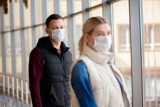 homem e mulher em pé com máscaras médicas