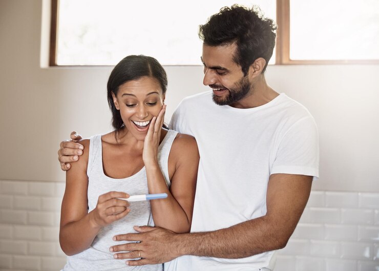 Foto homem e mulher entusiasmados em casa com sorriso de teste de gravidez e planejamento familiar na casa de banho boas notícias resultados surpresa e casal grávida com celebração de saúde bem-estar e feliz no casamento