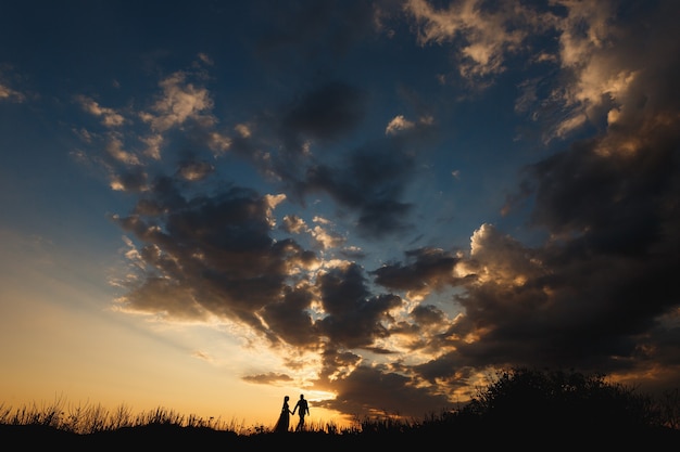 Homem e mulher estão caminhando no campo contra o lindo céu pôr do sol