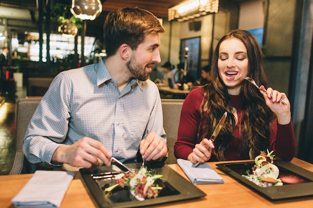 Foto homem e mulher estão comendo à mesa no restaurante e conversando entre si. eles estão desfrutando de companhia um do outro.