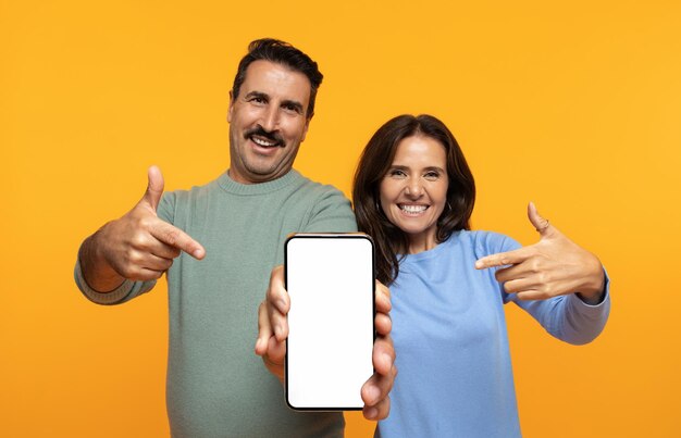 Foto homem e mulher europeus felizes e entusiasmados apontam o dedo para o smartphone