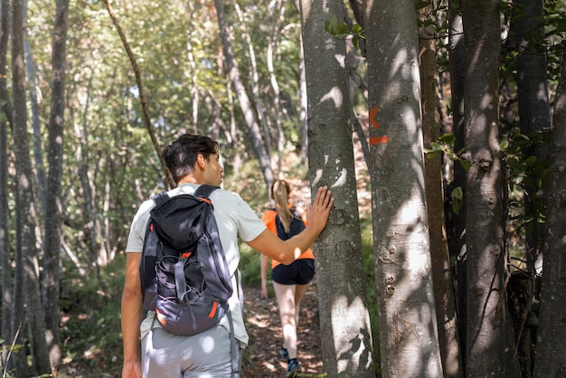 Homem e mulher explorando a natureza montanhosa caminhando ao longo de uma trilha florestal cercada por vegetação de verão