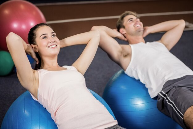 Homem e mulher fazendo abdominais na bola de fitness