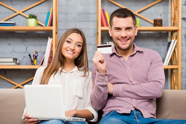 Homem e mulher fazendo compras pela internet com laptop e cartão do banco