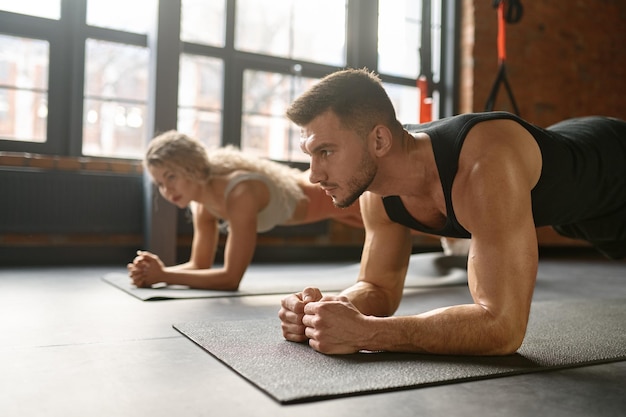 Homem e mulher ficam na prancha. treinamento em grupo na aula de ginástica do clube esportivo. foco no esportista. conceito de treino de fitness