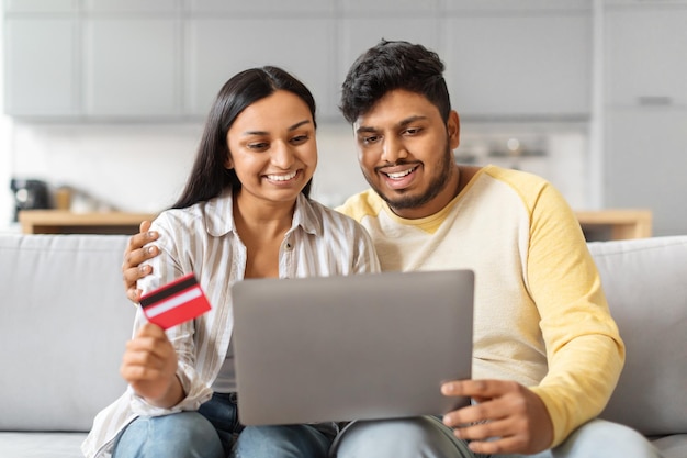 Homem e mulher indianos sentados no sofá olhando para o laptop