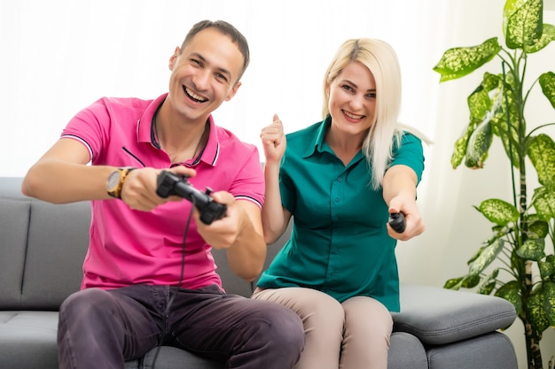 Homem e mulher jogando videogame com joystick em casa.