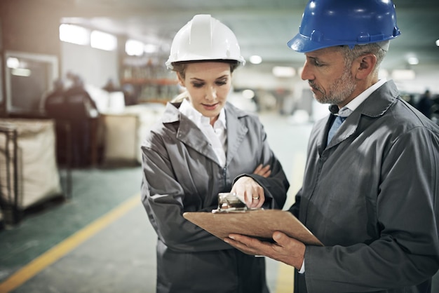 Homem e mulher lista de verificação com clipboard na fábrica para inspeção de qualidade ou verificações de segurança e monitoramento do processo Comunicação da equipe e quadro para informações de fabricação no armazém de impressão