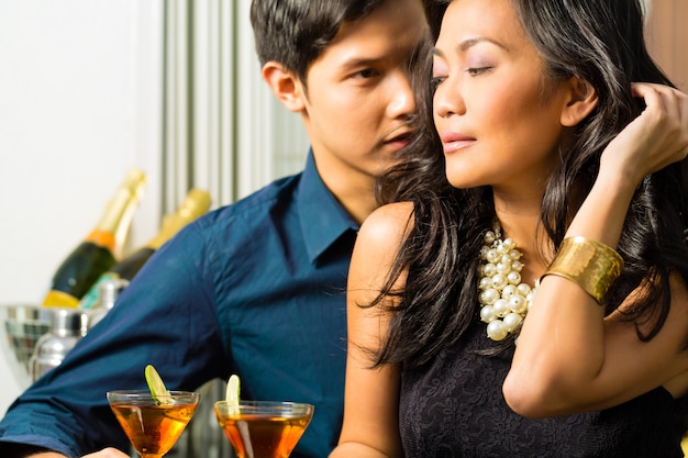 Homem e mulher na ásia no bar com cocktails