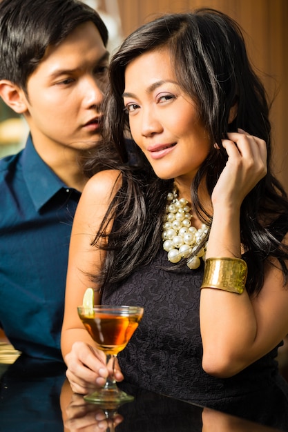 Homem e mulher na ásia no bar com cocktails