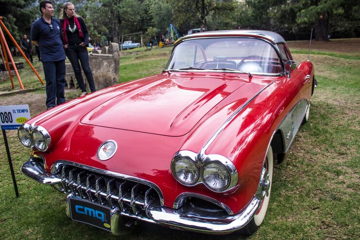 Foto homem e mulher olhando para um carro vintage vermelho exibido durante o show de automóveis