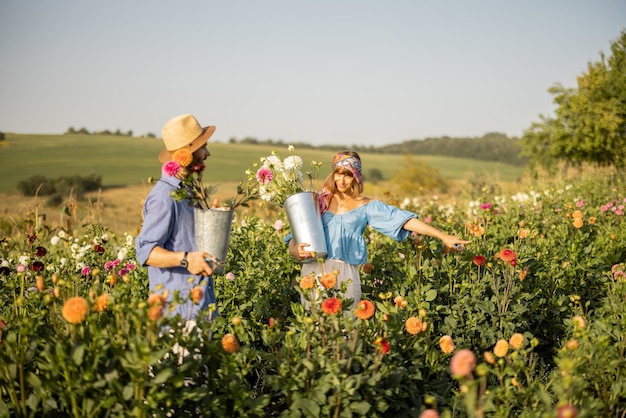 Homem e mulher pegam flores na fazenda ao ar livre