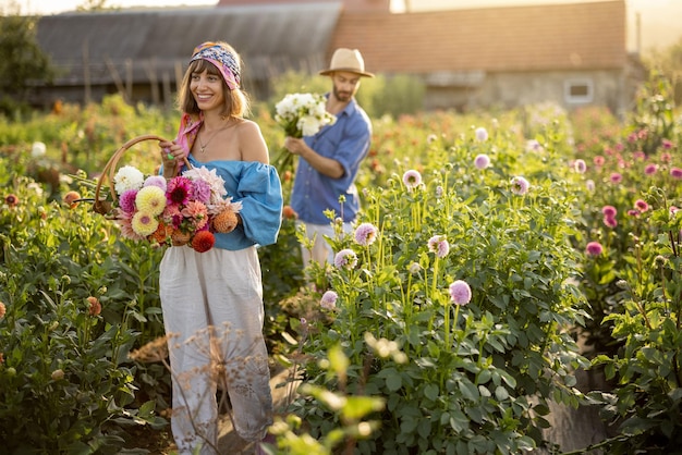 Homem e mulher pegam flores na fazenda ao ar livre