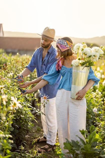 Homem e mulher pegam flores na fazenda ao ar livre