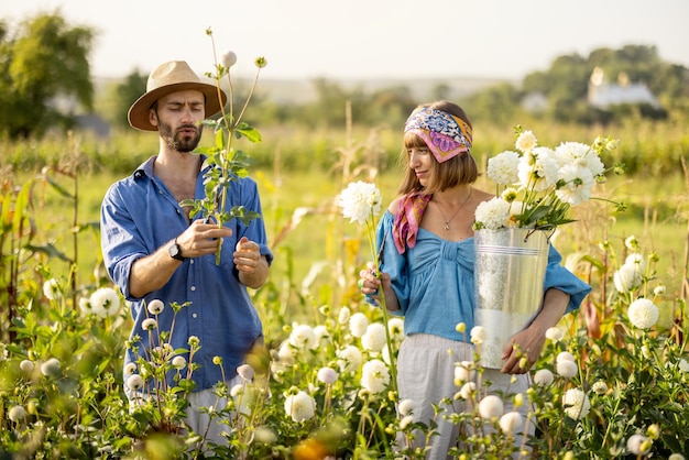 Homem e mulher pegam flores na fazenda ao ar livre